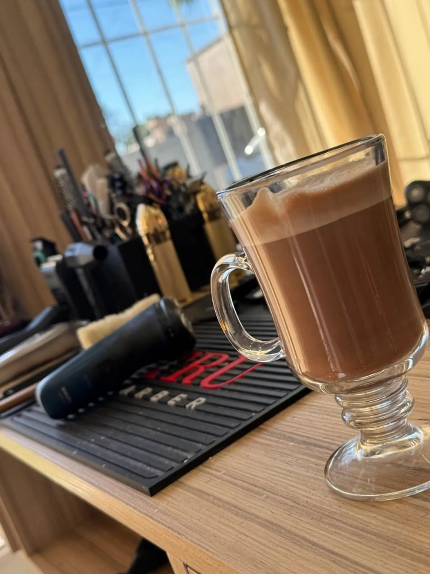 Café recién servido junto a herramientas de barbero sobre la estación de trabajo.