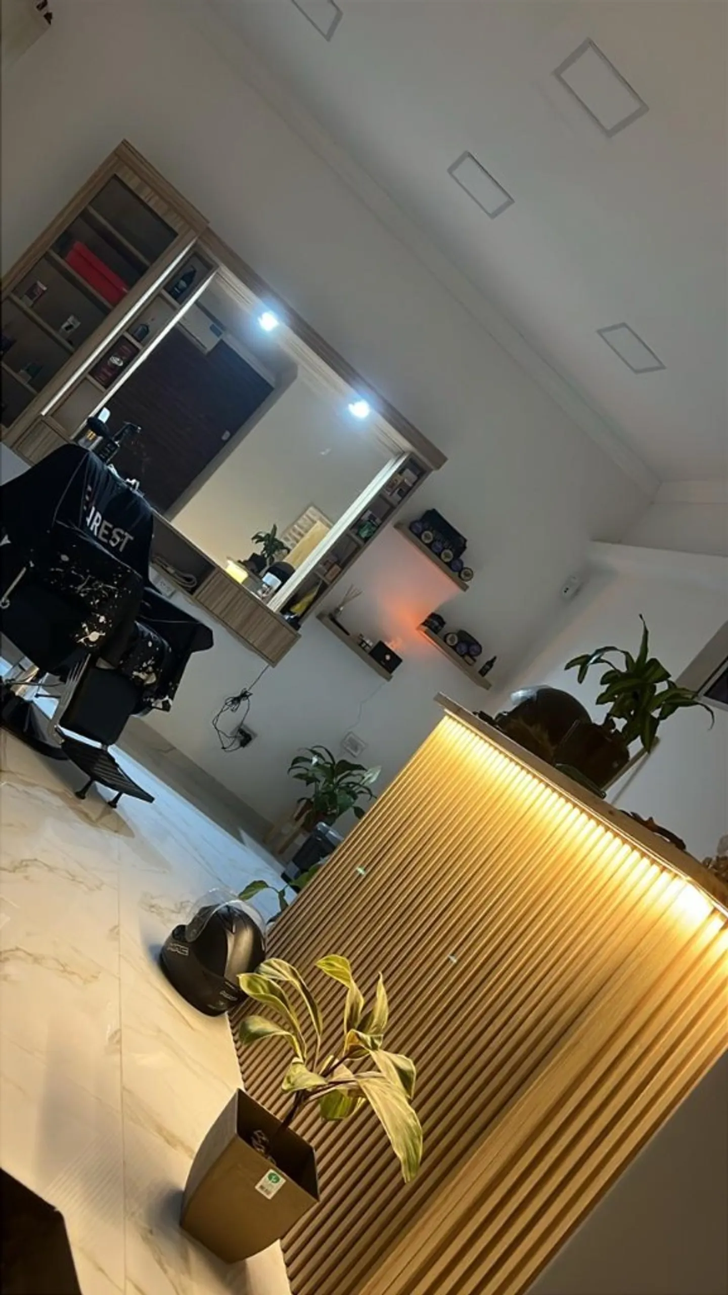Interior de Visage: estación de barbero, espejo iluminado y recepción con luz cálida.